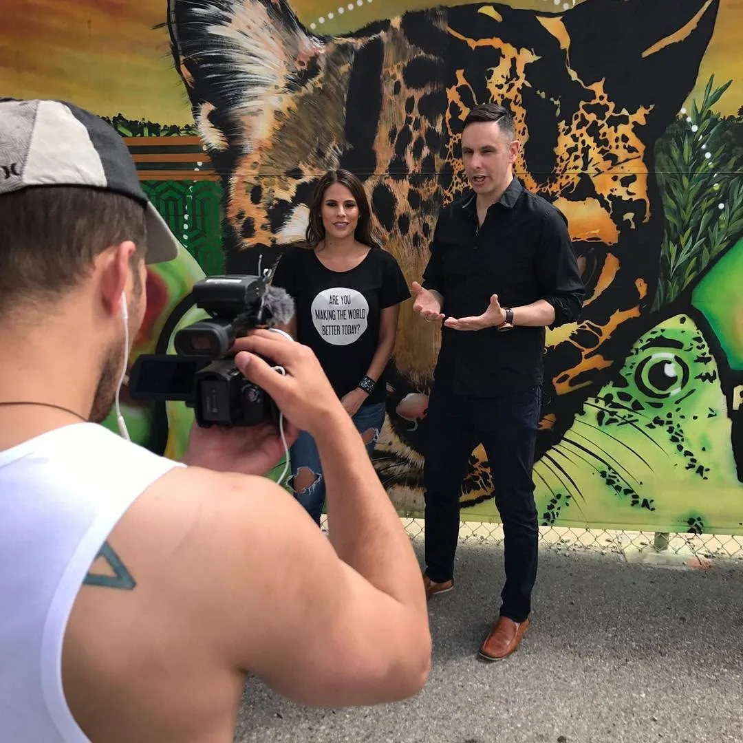 Shane James being filmed on location in front of a painted mural