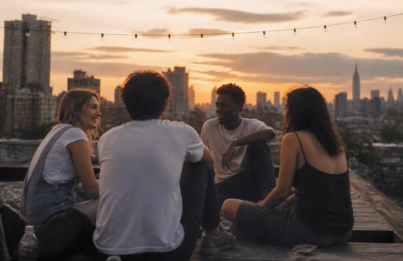 Friends talking together on a rooftop at sunset
